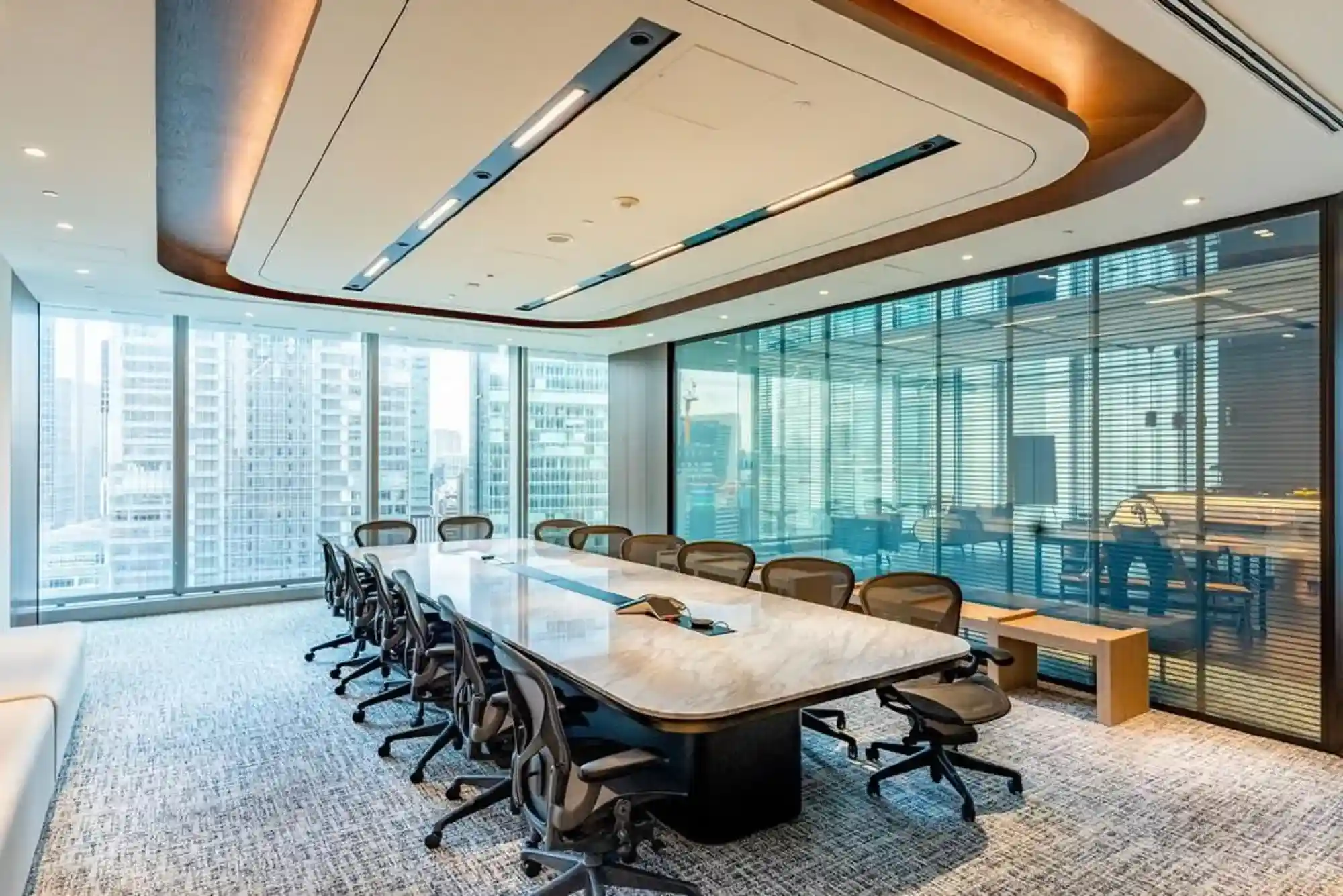 Spacious meeting rooms in Abu Dhabi with marble tables, ergonomic chairs, and skyline views through floor-to-ceiling windows.